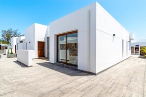 Un bâtiment moderne doté d’un toit plat, de grandes portes coulissantes en verre et d’une façade en pierre.