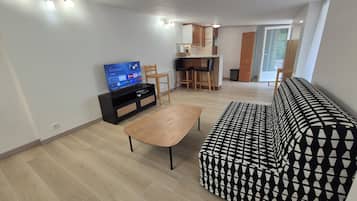 Olohuone, jossa on sohva, sohvapöytä, televisio sekä ruokailutila, jossa on tuoleja ja pöytä.