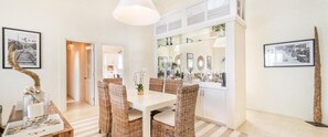 A dining area with wicker chairs and a white table, a kitchen with white cabinets, and a hallway leading to another room. - Little Good Harbour House- 3BR Ocean Front Villa (St. Peter)