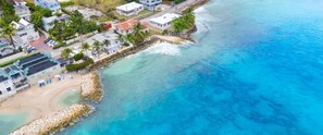 Zona residencial costeira com casas, uma praia e um molhe rochoso.