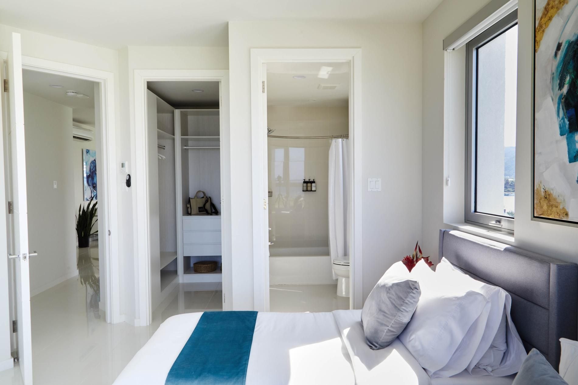 Un dormitorio con cama, ventana, ducha y vestidor.