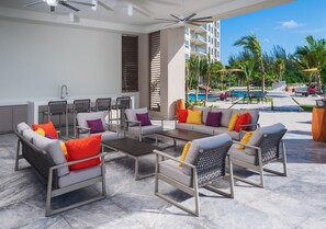 Un espace de détente extérieur moderne avec vue sur la piscine, comprenant un ensemble de canapés, des fauteuils et une table basse.
