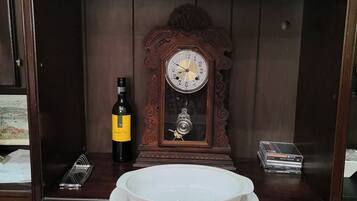 Un meuble en bois contenant une horloge, une bouteille et une pile de DVD.