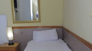 A hotel room with a bed, a nightstand with a lamp, a mirror, and a chair.