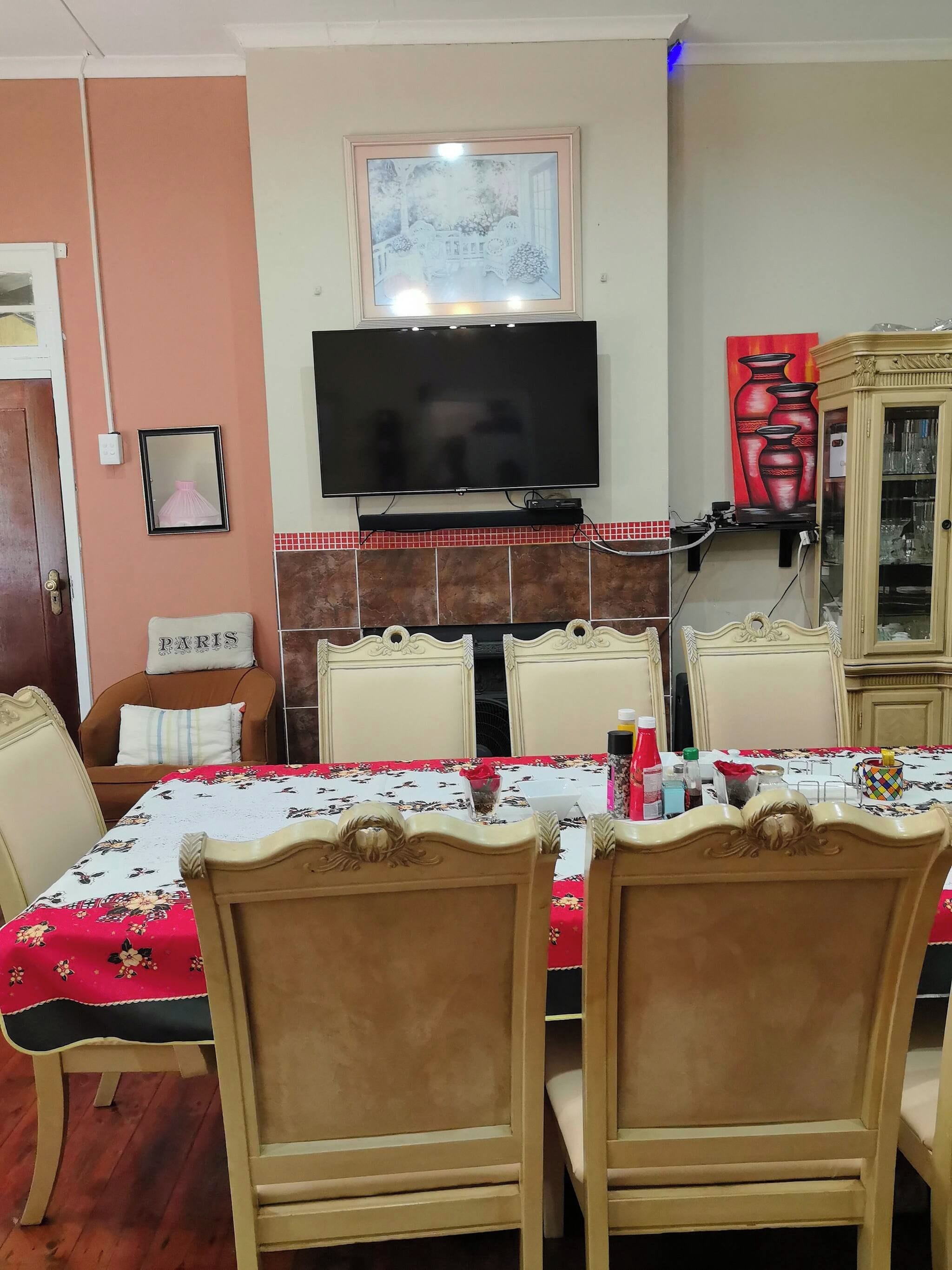 Un coin repas avec une table dressée pour quatre personnes, un téléviseur placé au-dessus de la table et un meuble contenant de la verrerie.