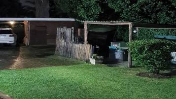 Vista nocturna de una zona residencial con césped cuidado, una valla de madera y un garaje.