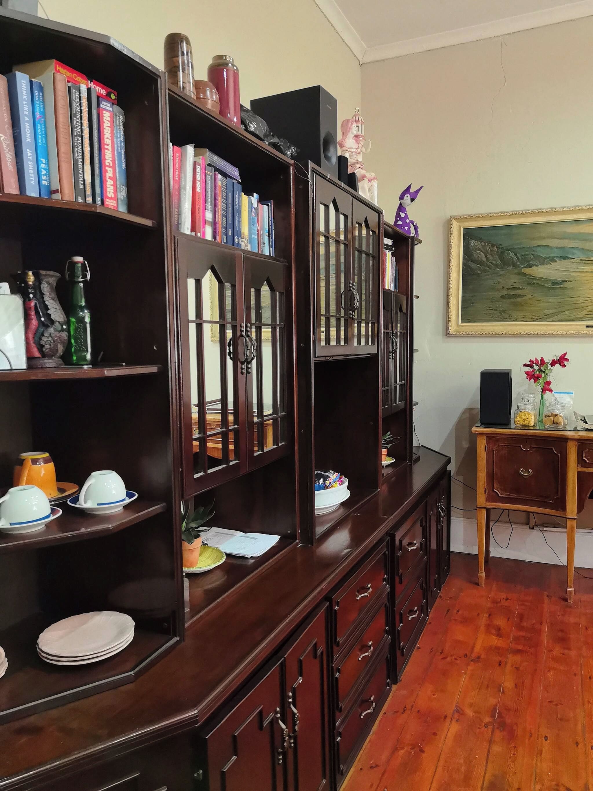 Una estantería de madera con libros, una estatua decorativa de elefante y un cuadro de paisaje enmarcado en la pared.