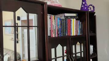 A bookshelf with books, a figurine, and a small purple toy.