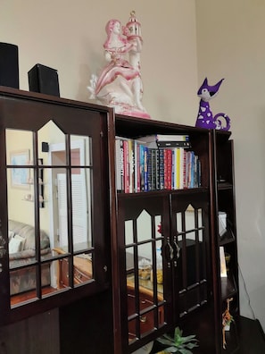 Una estantería con libros, una figurita y un juguete morado pequeño.