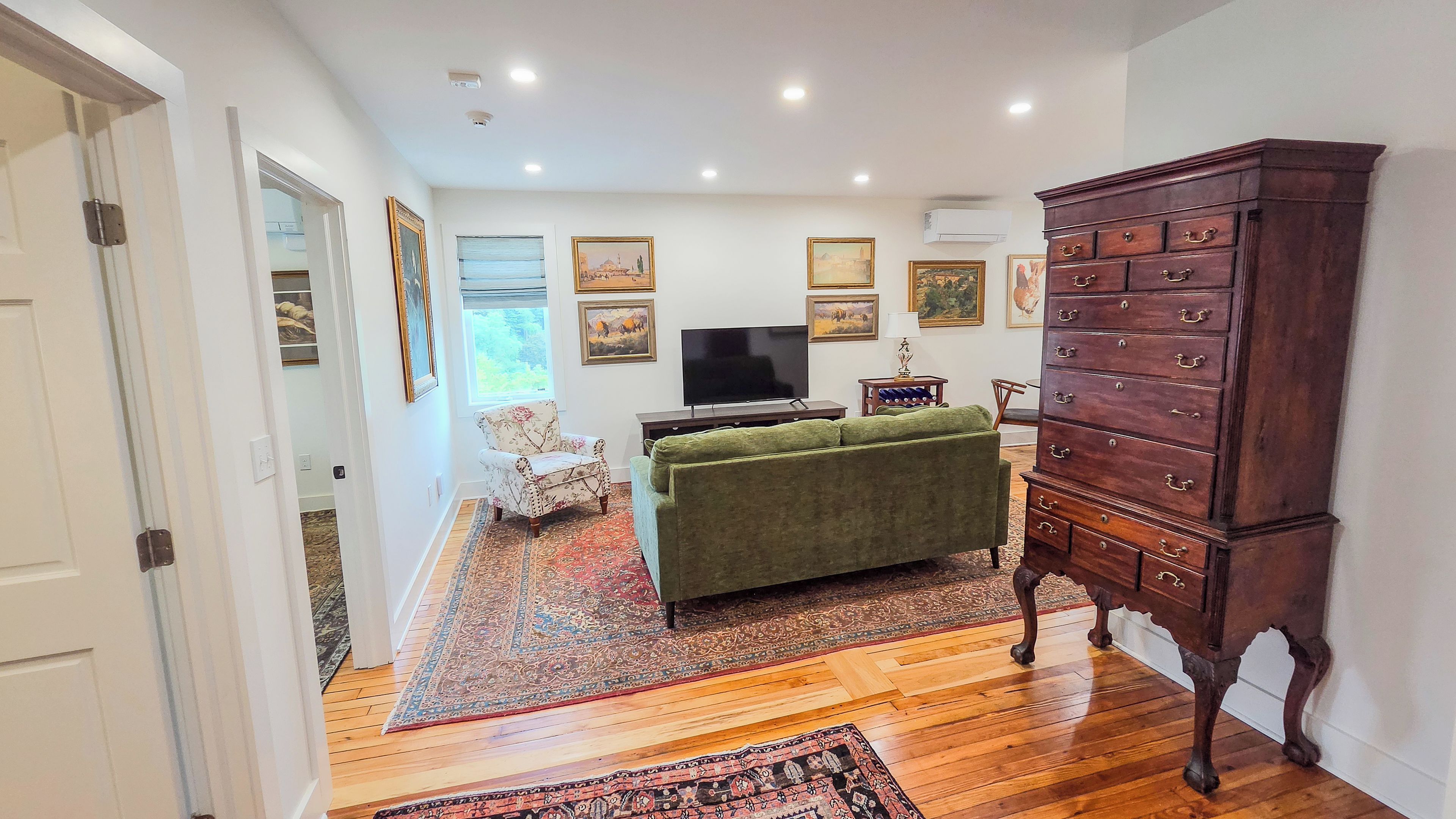 A living room with a green sofa, wooden dresser, and a flat-screen TV.