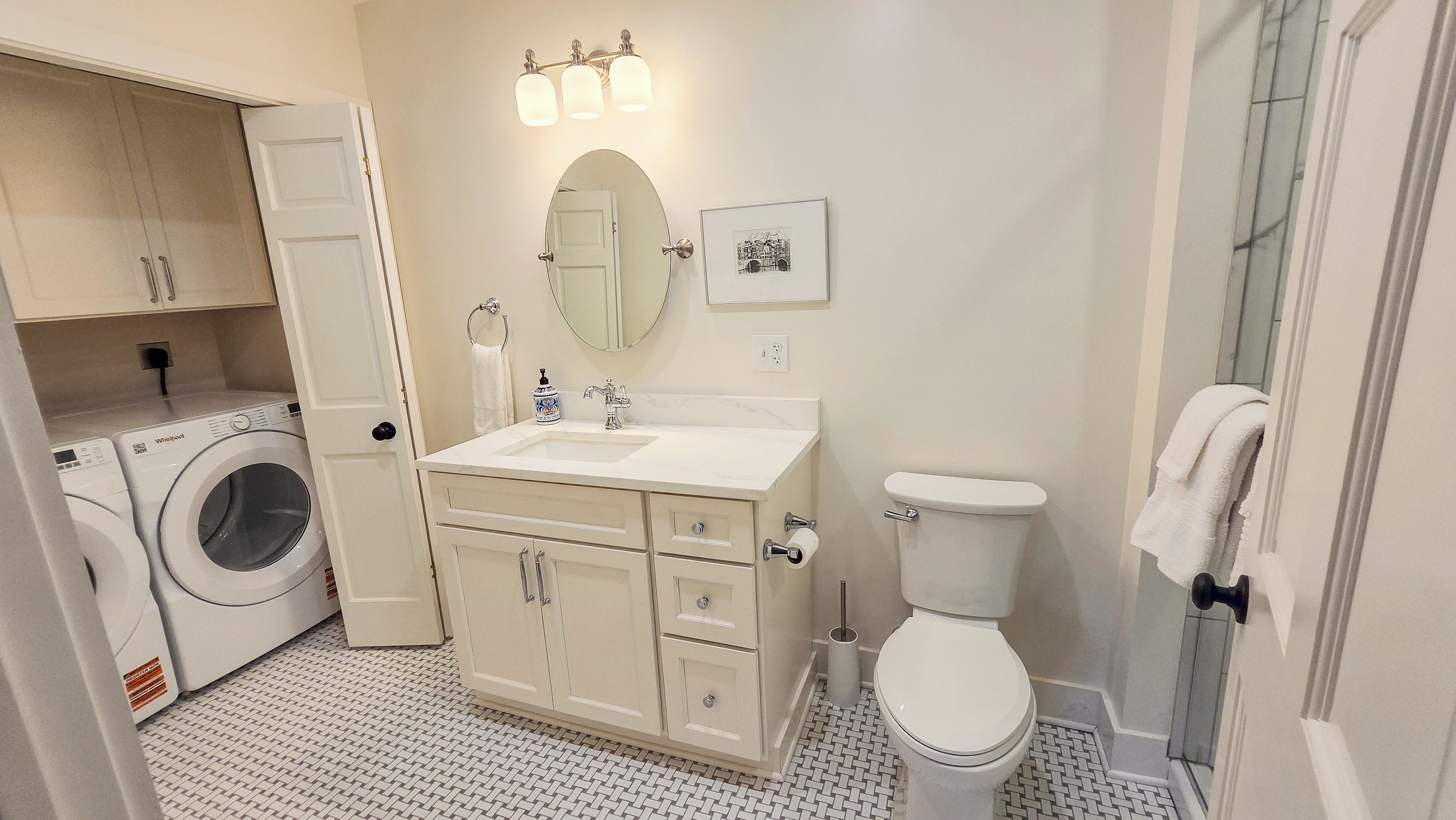 A bathroom with a washing machine, a toilet, a sink, and a mirror.