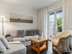 Ein modernes Wohnzimmer mit einer Couch, einem Holztisch und einem Korbstuhl.