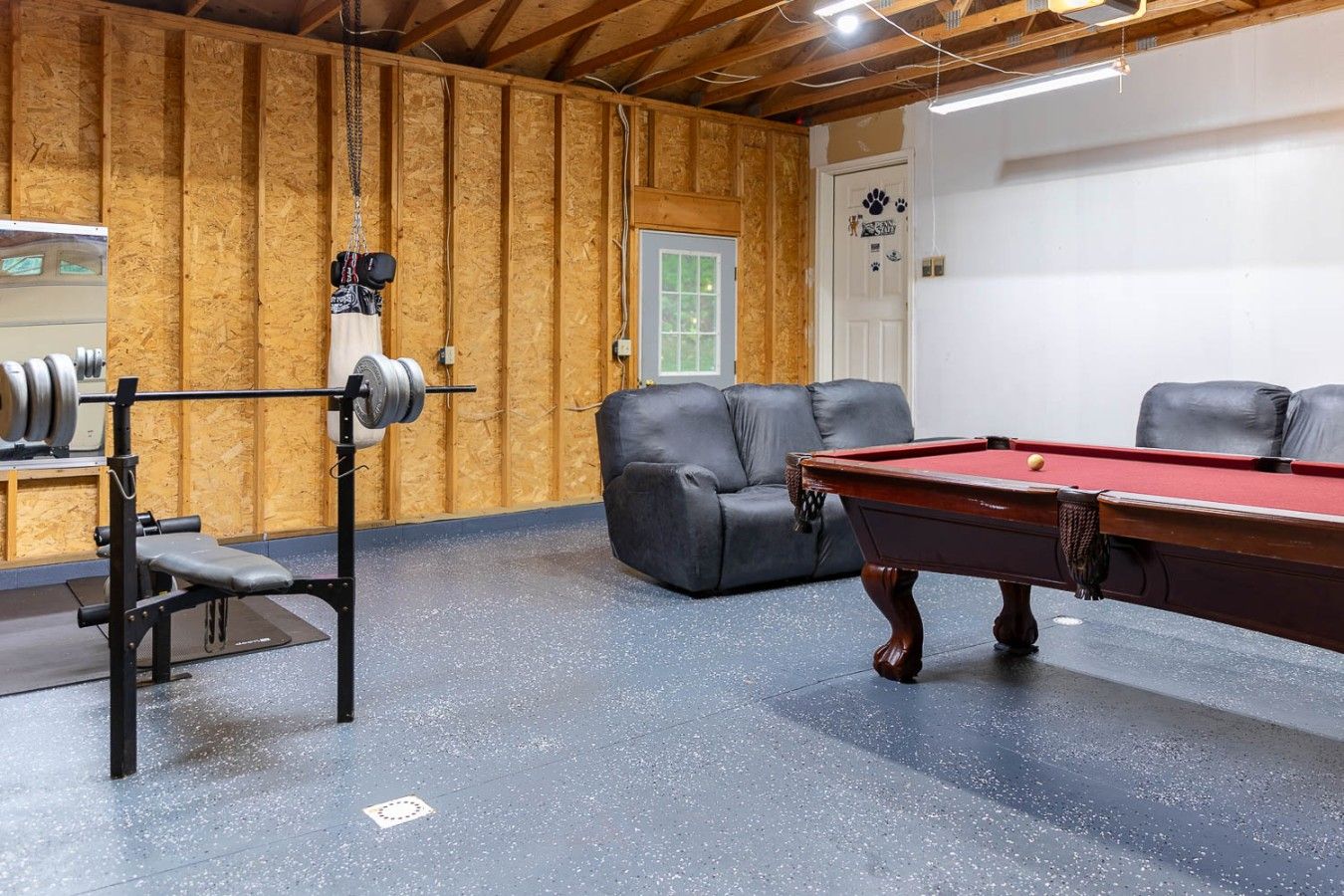 Une pièce équipée d’une table de billard, d’un banc et d’un espace dédié à la musculation.