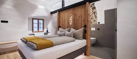 Une chambre moderne avec un grand lit, une tête de lit en bois et une petite fenêtre.