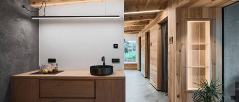 Una cocina moderna con una isla de madera, un lavamanos negro y vistas al exterior.