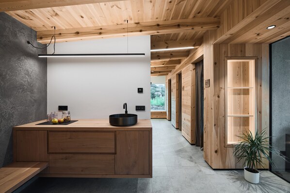 A modern kitchen with a wooden island, a black sink, and a view of the outdoors.