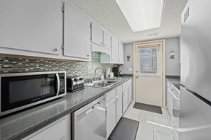 A modern kitchen with white cabinets, a microwave, toaster, and a refrigerator. - Guest Cottage 61- 4BR House- Community Pool (Myrtle Beach)