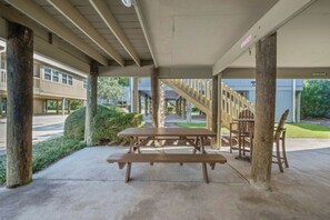Ein überdachter Picknickbereich im Freien mit Bänken und Stühlen, einer Treppe und einem Gebäude im Hintergrund.