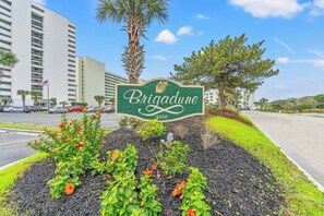 A sign for Brigadene with a clear view of the surrounding area including a parking lot, buildings, and a road. - 2BR/2BA Oceanfront- Pool- Brigadune I 11D (Myrtle Beach)