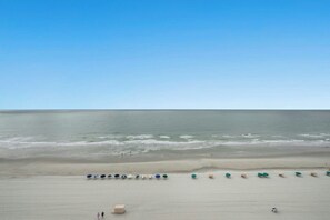 A beach with a row of umbrellas and a few people walking. - 2BR/2BA Oceanfront- Pool- Brigadune I 11D (Myrtle Beach)