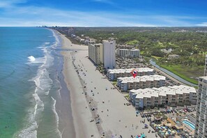 Un hotel a la costa amb accés directe a la platja, diversos edificis alts i un riu que discorre paral·lelament a la sorra.