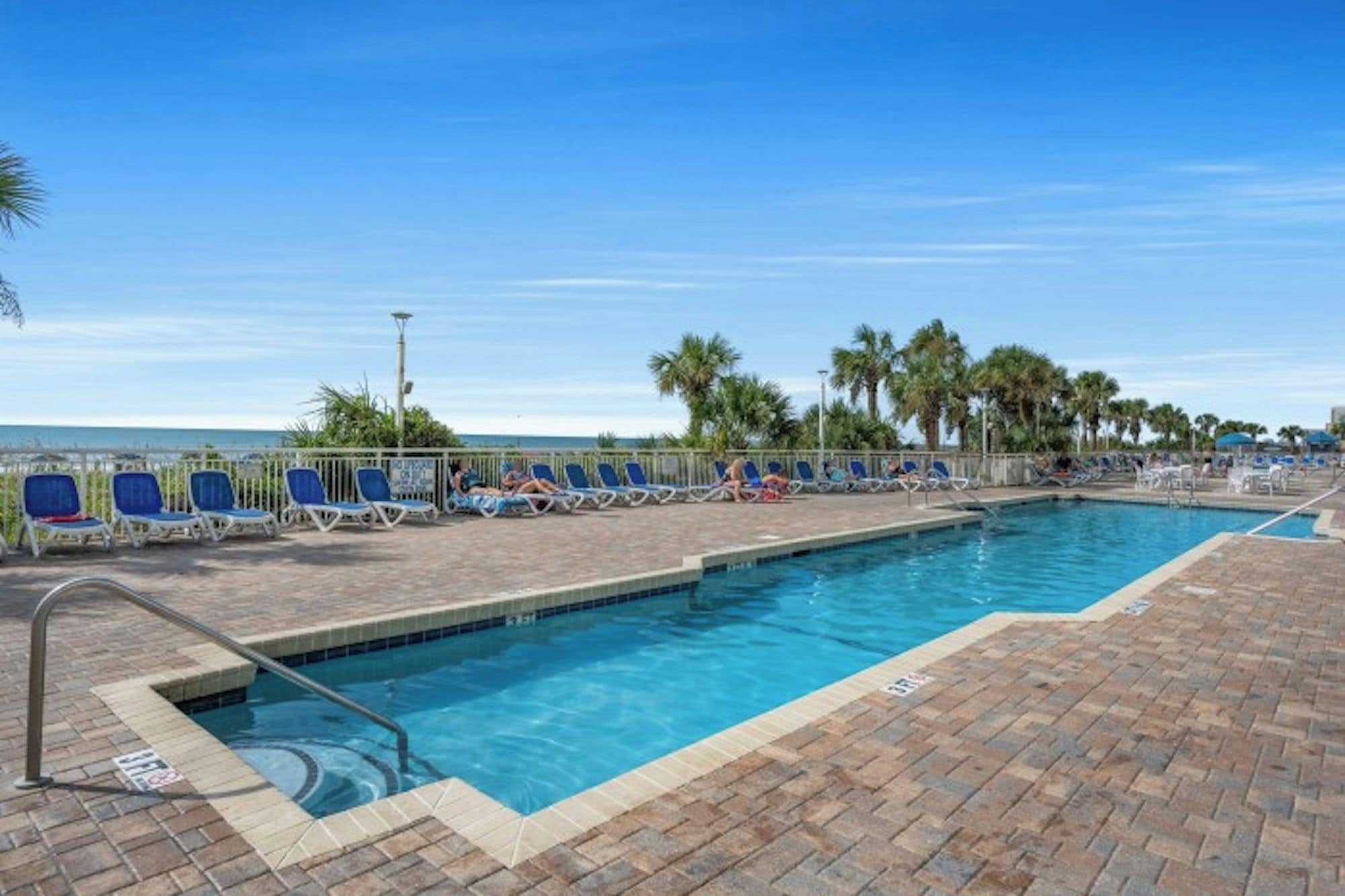 A swimming pool with lounge chairs and a view of the ocean.