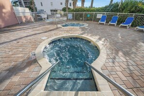 A hot tub area with a pool, lounge chairs, and a brick patio. - Bay Watch 735- Oceanfront 1BR- Pools (North Myrtle Beach)