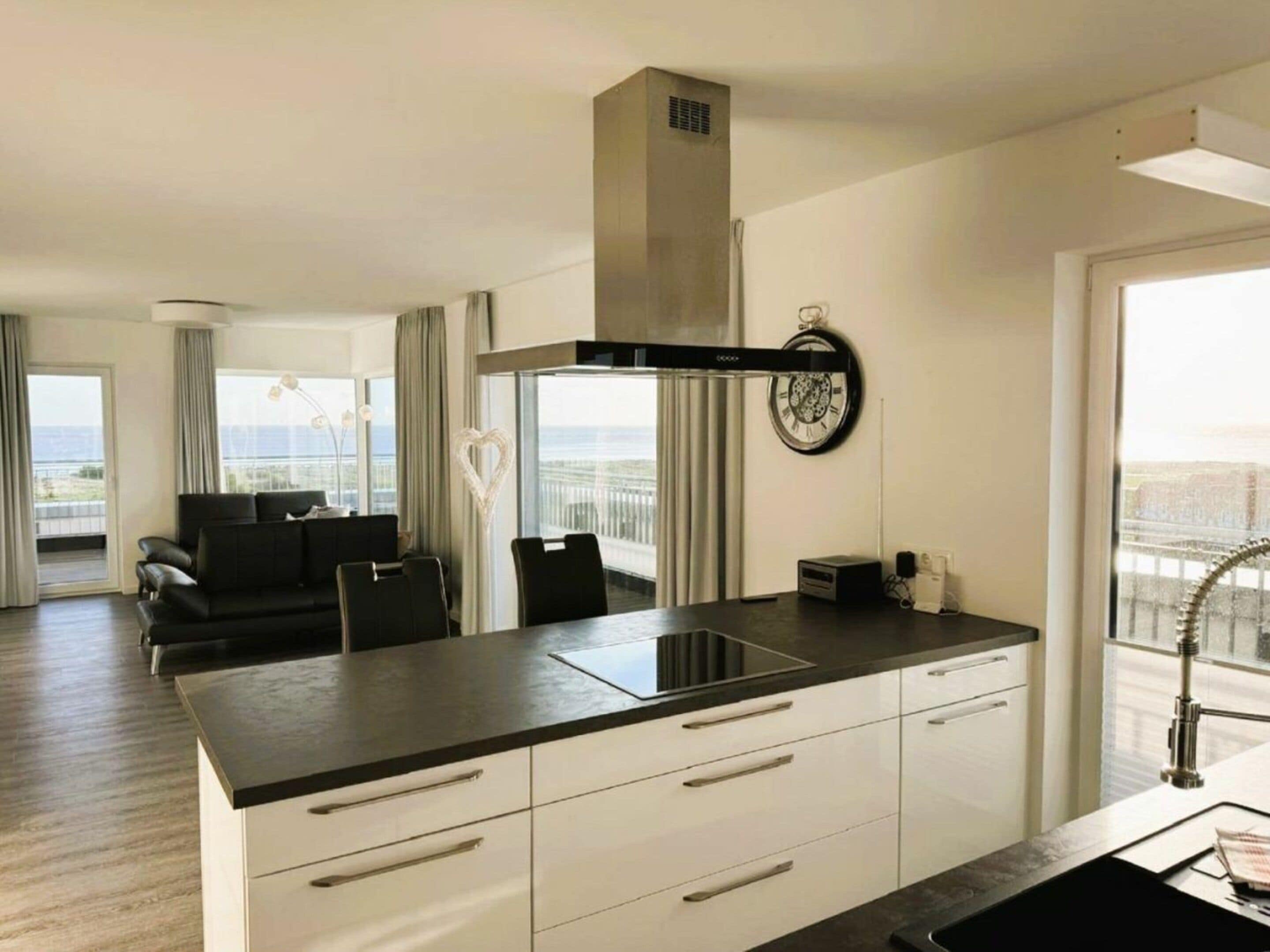 A modern kitchen with a central island, white cabinetry, and a view of the ocean.