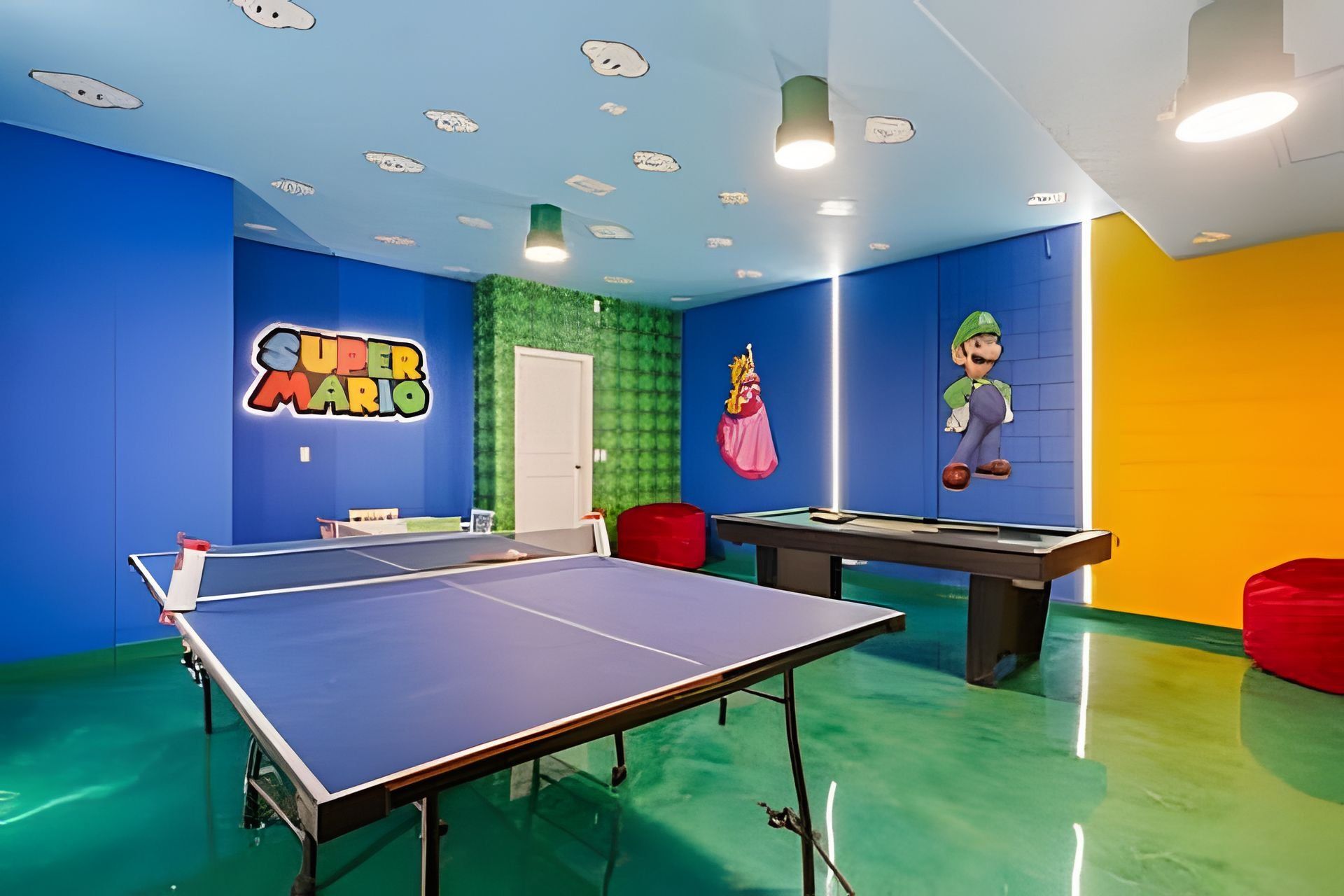 Een kamer met een tafeltennistafel, een pooltafel en muren versierd met Super Mario personages.
