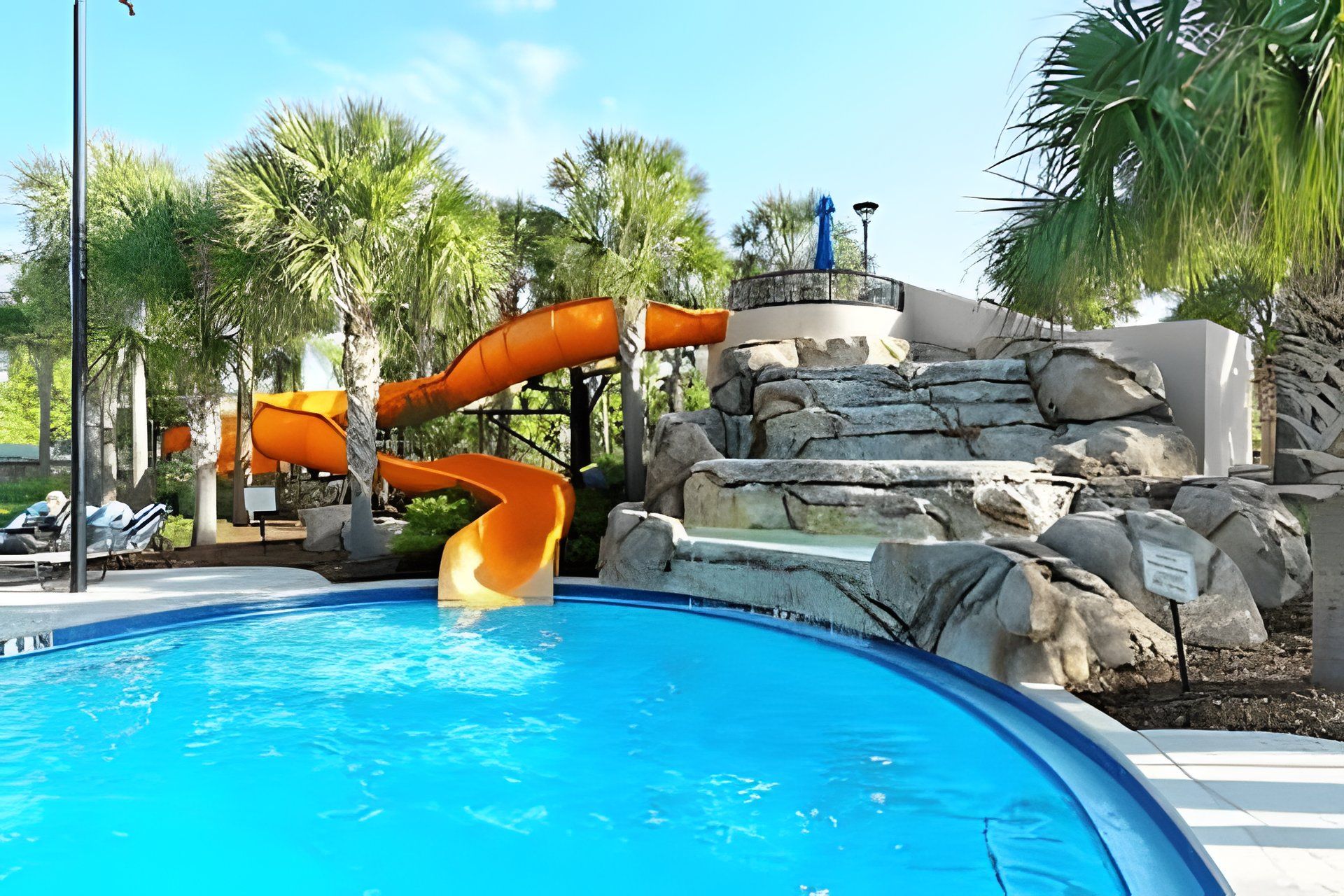 Una piscina con tobogán y una estructura rocosa.