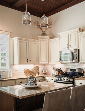 A kitchen with white cabinets, a granite countertop, a stove, and a microwave. - Peaceful Home Just 10 Minutes from Oxford Square (Oxford)