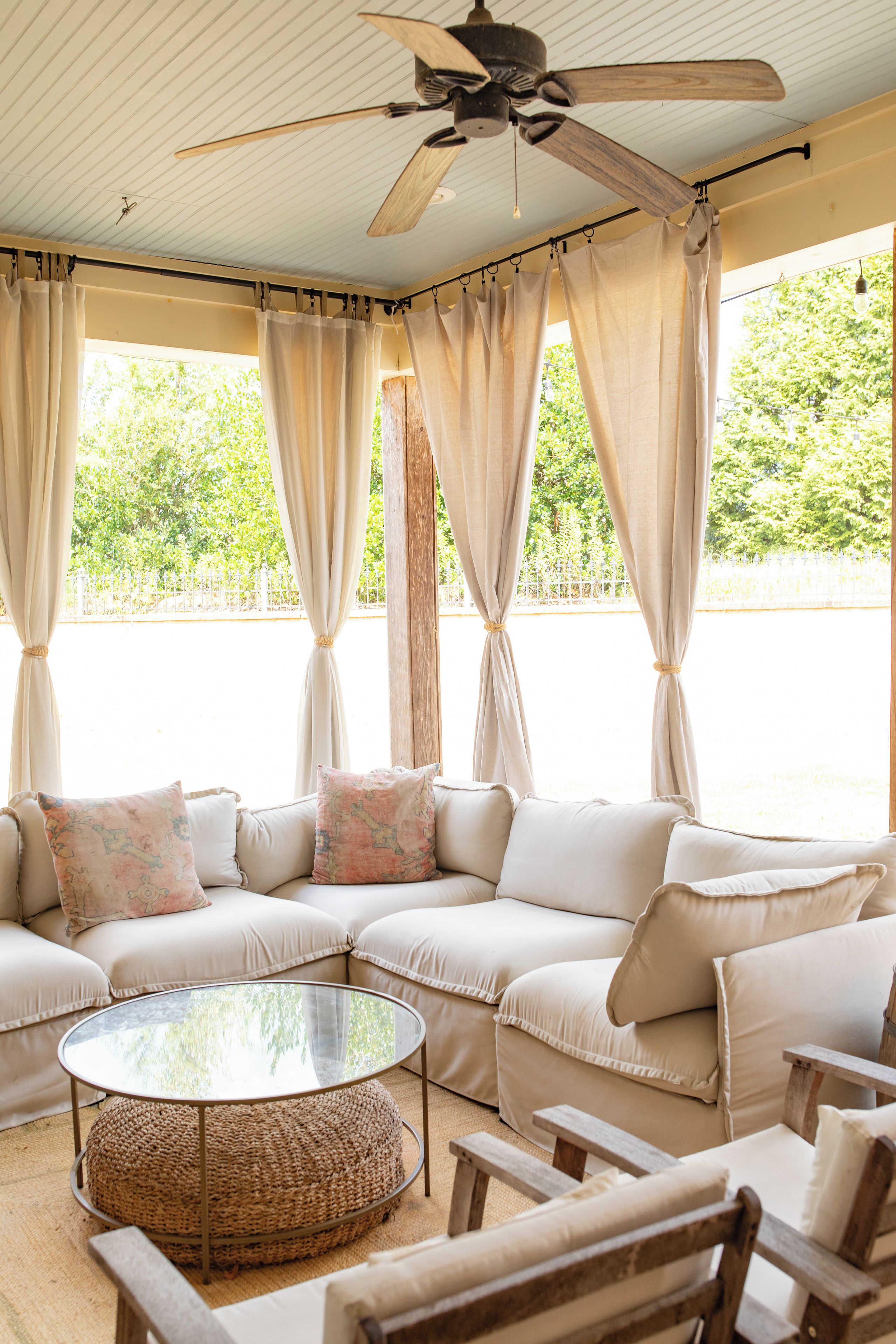 A room with a sectional sofa, a round coffee table, and a ceiling fan.