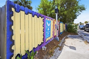 A fence with a colorful design and a sign indicating 'Marriott Banyan 2054 Coastal Highway.' - 1BR · Sleeps 3 · Dog-Friendly · Shared Hot Tub (Saint Augustine)