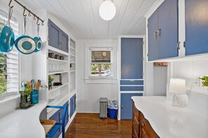Open shelves of mugs and glasses and a rail of pans keep everything in sight in this compact, cheerful blue kitchenette. - 1BR · Sleeps 3 · Dog-Friendly · Shared Hot Tub (Saint Augustine)