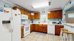 A kitchen with wooden cabinets, a white refrigerator, a microwave, a stove, and a sink. - The Ocean Rancher - 40 Woodland Ave (Ocean View)