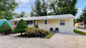 A single-story motel with a gravel driveway, two black chairs, and a small garden with a lamp post. - The Ocean Rancher - 40 Woodland Ave (Ocean View)
