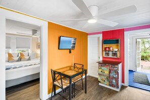 Une pièce comprenant un lit, un bureau, une chaise, un téléviseur et un petit meuble de rangement.