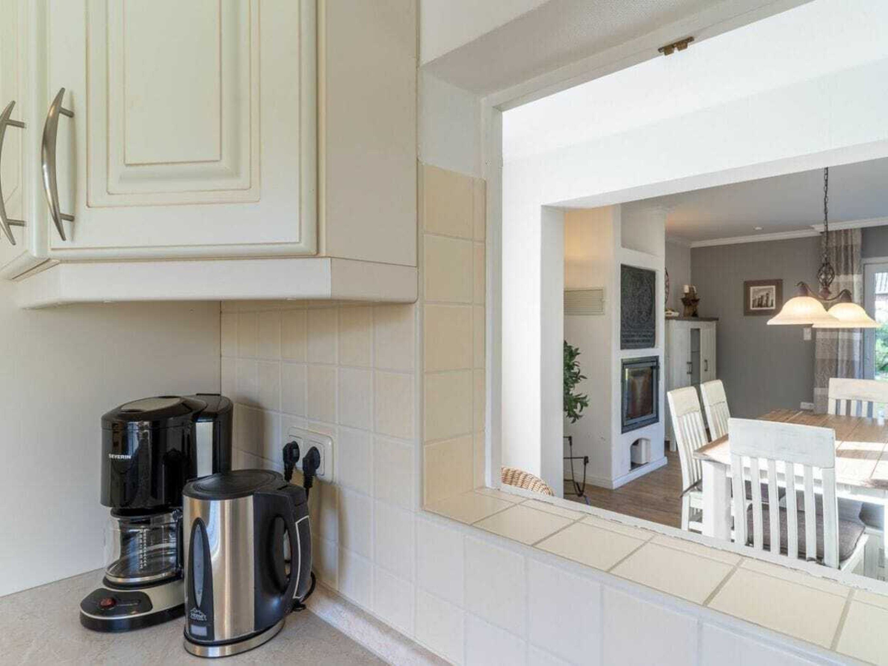 A kitchen with white cabinets, a coffee maker, and a kettle.