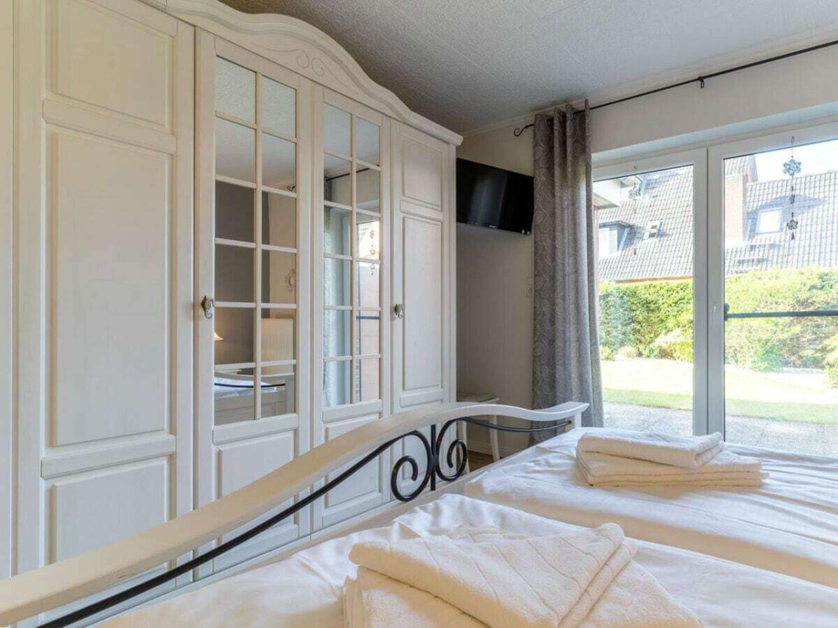 A bedroom with a bed, a wardrobe, and a television.