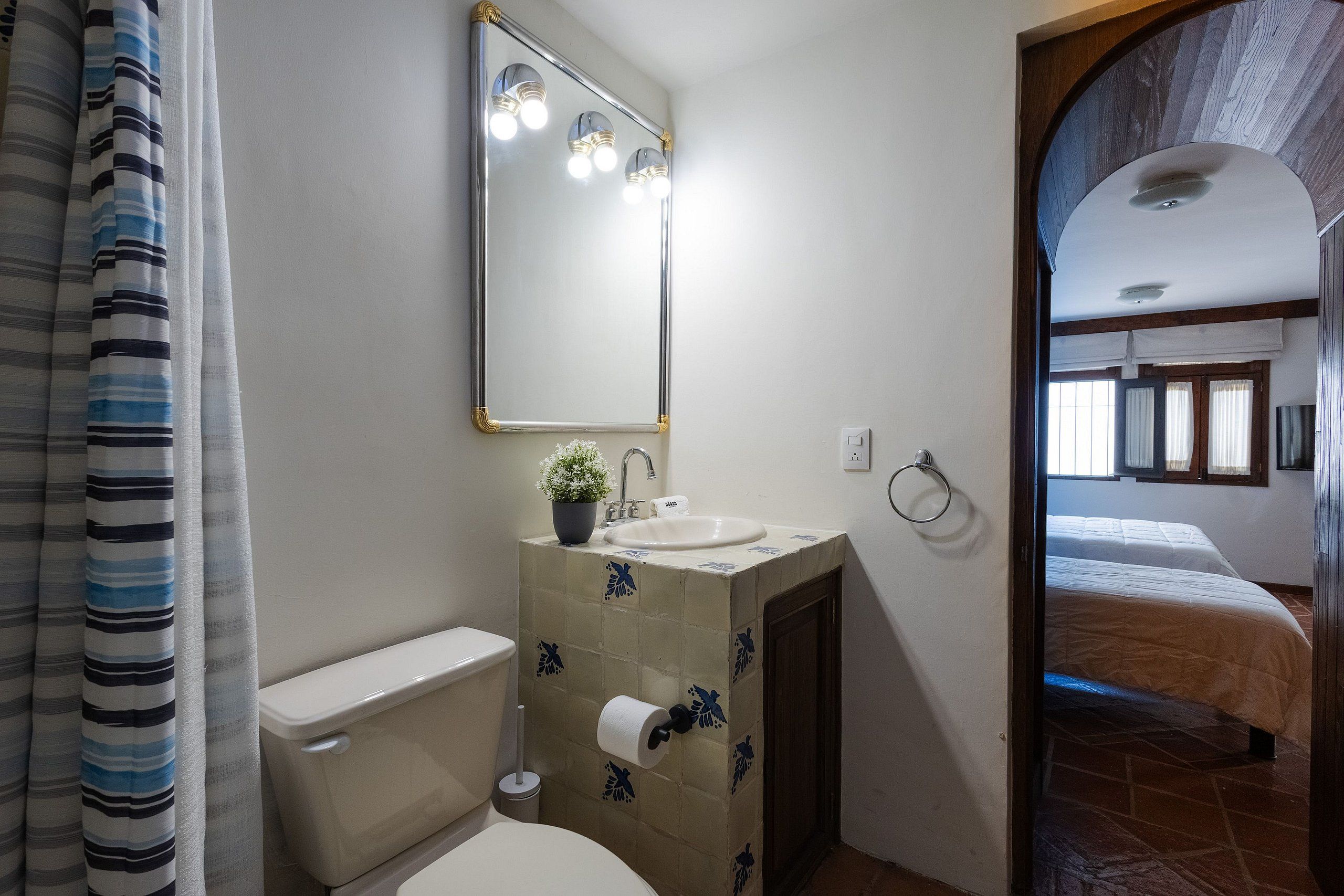A bathroom with a toilet, sink, and mirror.