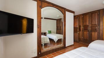 A hotel room with a large mirror, a bed, a television, and wooden wardrobes.