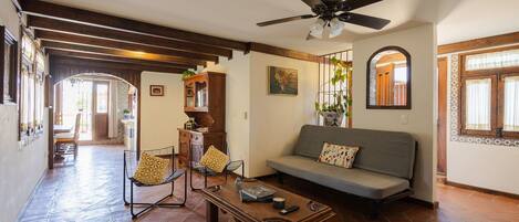 A spacious living area with a sofa, chairs, a coffee table, and a ceiling fan.