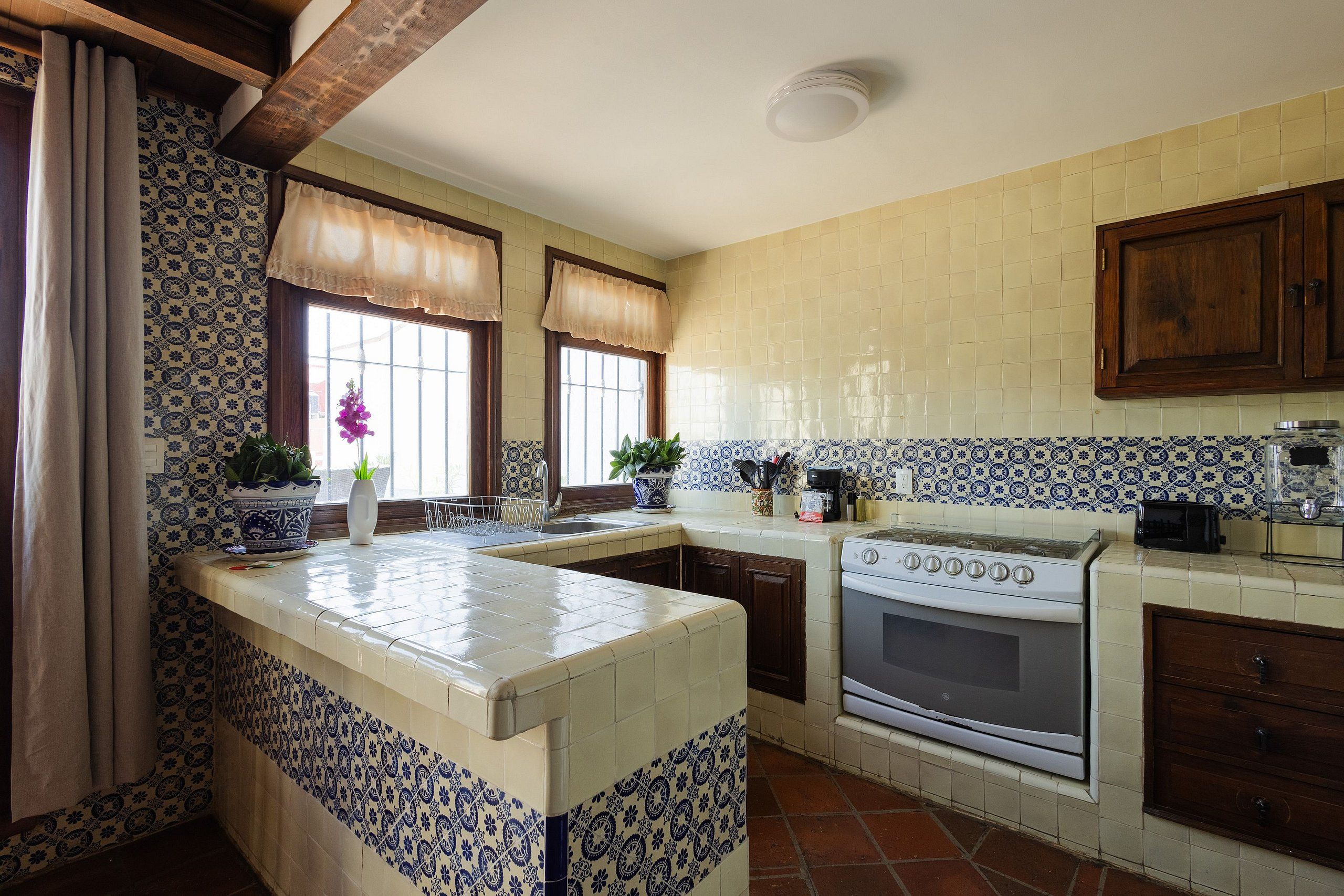 Una cocina con salpicadero de azulejos, estufa y lavabo.