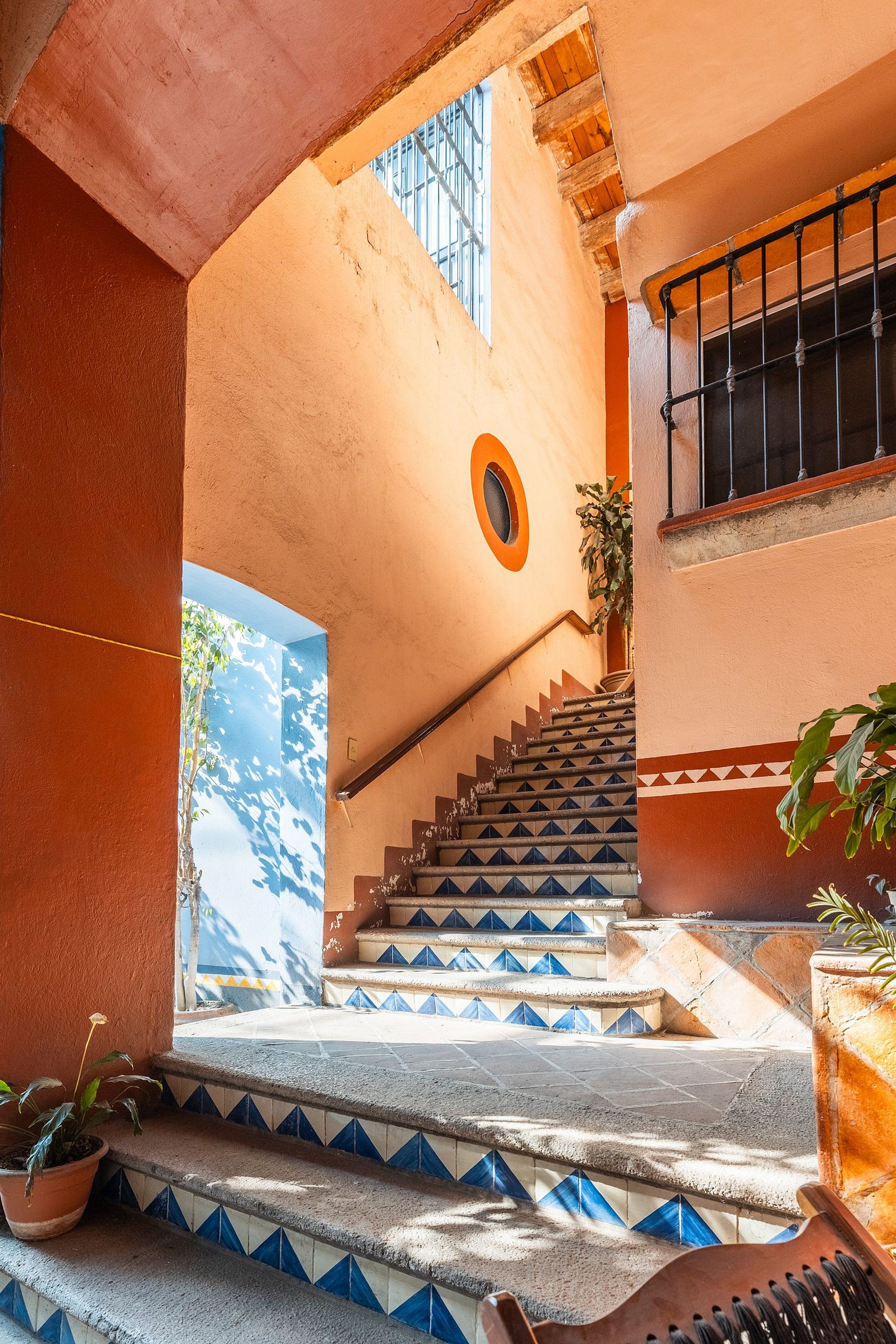 A staircase with blue and white patterned steps leading to a balcony with a view of the sky.