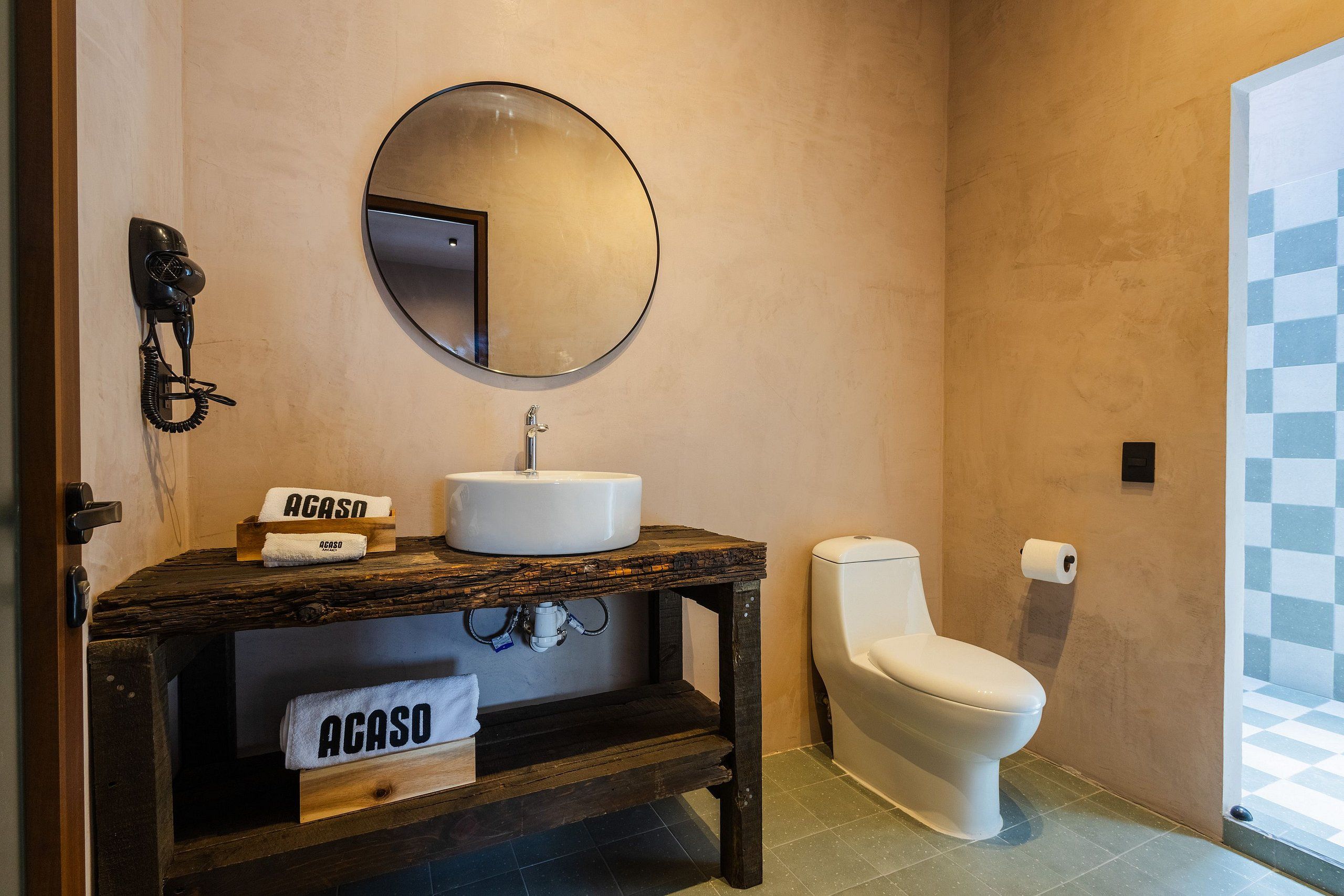 A bathroom with a round mirror, a sink, a toilet, and a towel rack with towels.