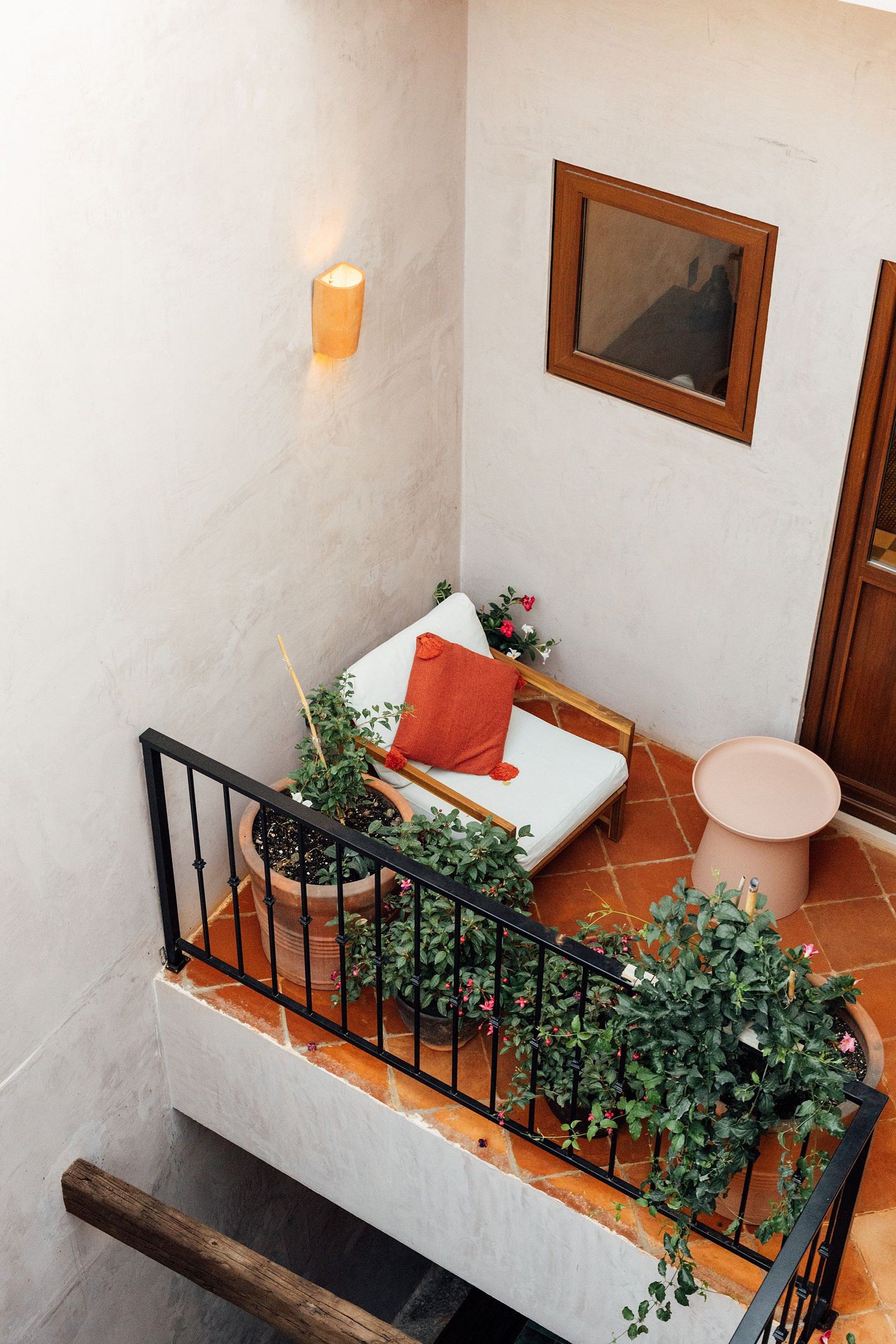 A small, cozy room with a white sofa, a wooden bench, and a potted plant.