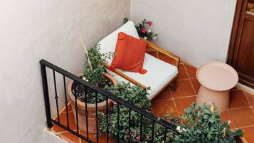 A small, cozy room with a white sofa, a wooden bench, and a potted plant.