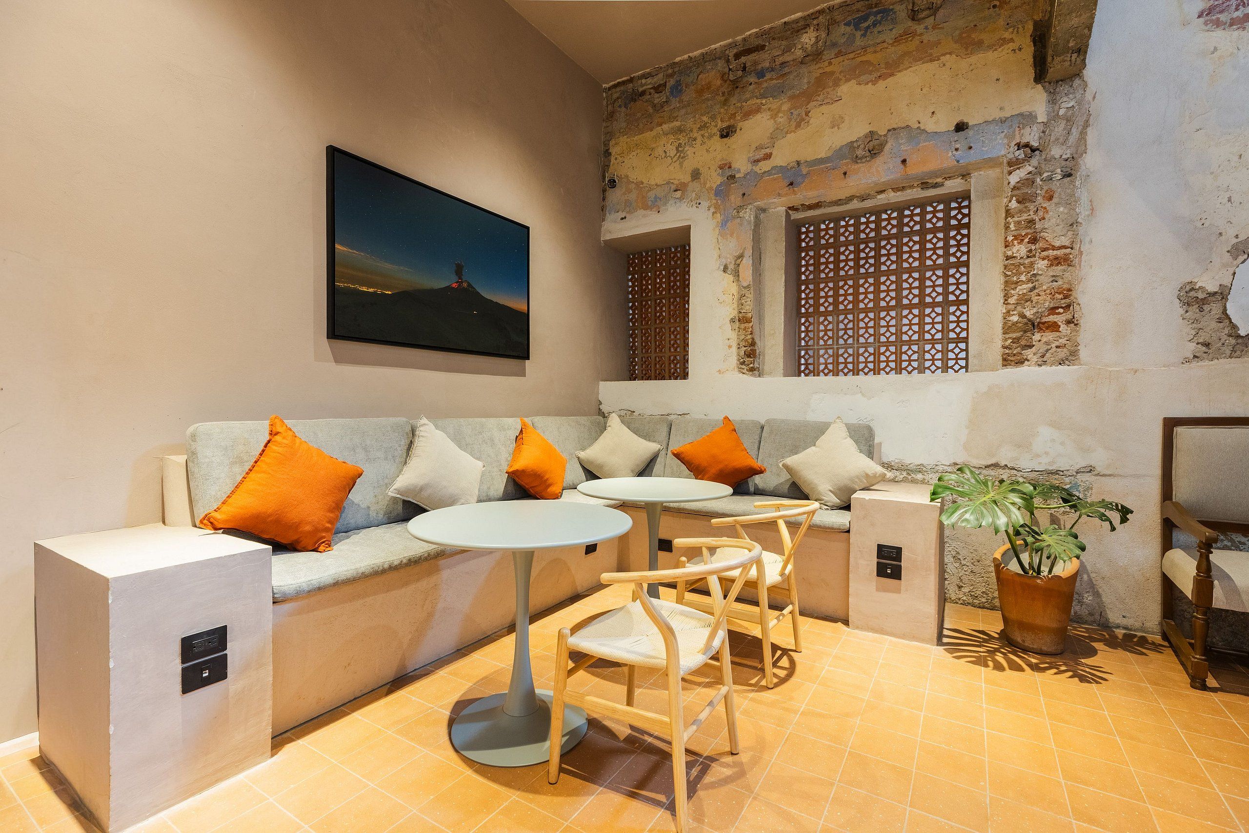 A cozy seating area with a sofa, two side tables, and chairs, a potted plant, and a wall-mounted picture.