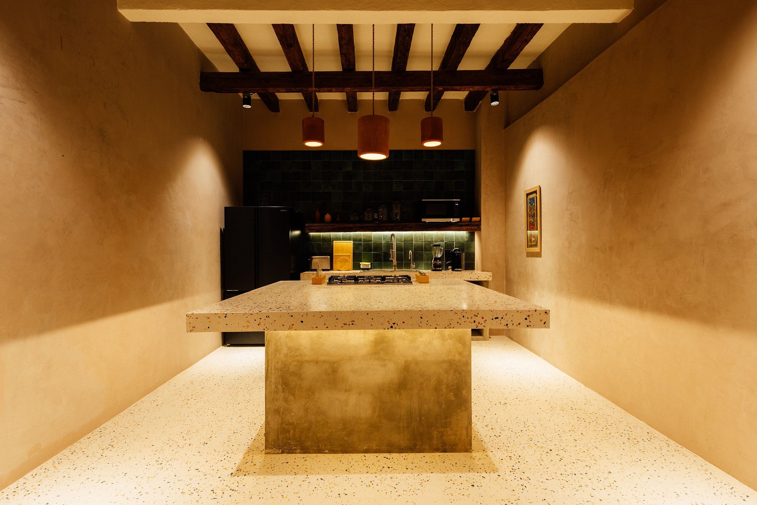 A kitchen with a central island, dark cabinetry, and pendant lighting.