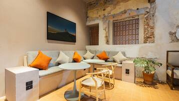 A cozy seating area with a sofa, two side tables, and chairs, a potted plant, and a wall-mounted picture.